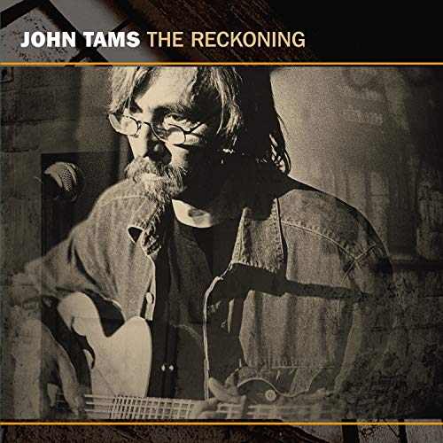 "Album cover: man in black jacket, red building background, 'John Tams The Reckoning' text."