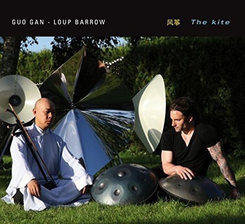 "Album cover featuring two men sitting on grass with metal instruments and a kite."