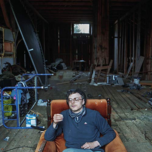 CD cover featuring a man in glasses seated in an armchair, indoors.