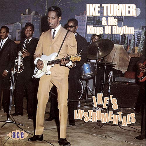 Ike Turner and his band performing on stage in suits with instruments.