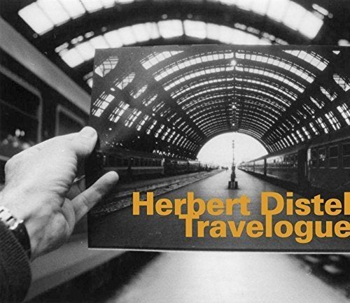 "Hand holding a CD cover with a black-and-white train station image and orange text."