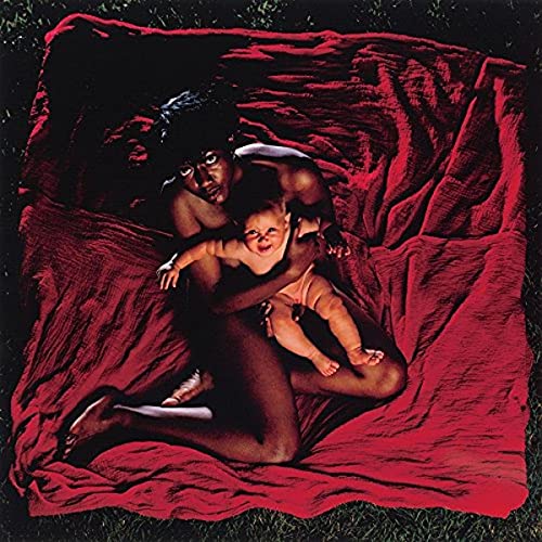 Album cover: two people embraced on red fabric, dark background.