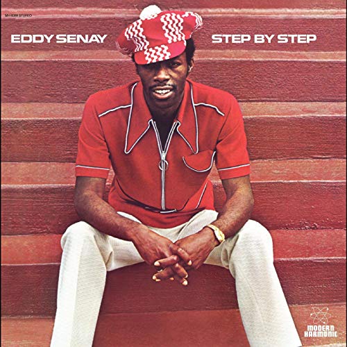 "Album cover featuring a man sitting on red stairs, wearing a red shirt and hat."