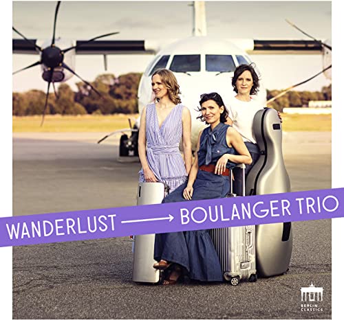 Three women with instruments and luggage in front of a small plane.