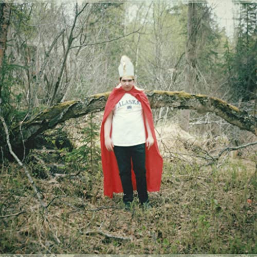 Person in red cape and pointed hat standing in a forest.