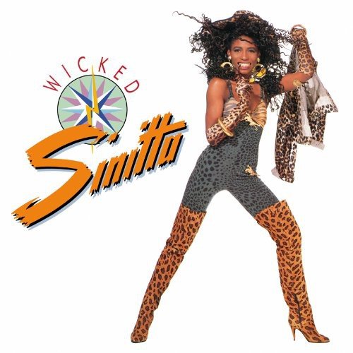 "Album cover with Sinitta in leopard-print boots and gray outfit, dancing."