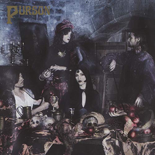 Four people in dark clothing pose around a still life with skulls.