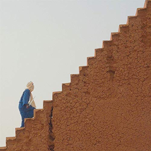 Person in blue climbs earthen steps against a pale sky.