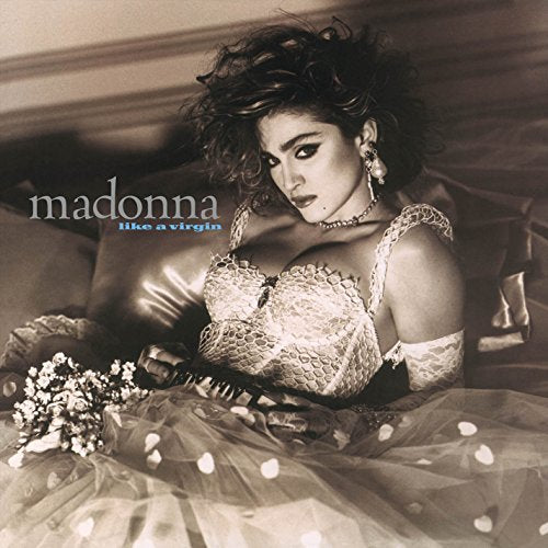 Madonna album cover: woman in white dress holding flowers, sitting on a leather sofa.