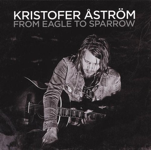 Black and white vinyl album cover featuring a man playing an acoustic guitar.