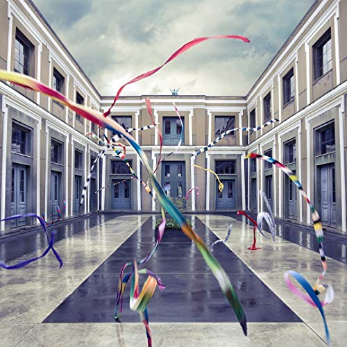 Colorful ribbons floating in a courtyard surrounded by a symmetrical grey building.