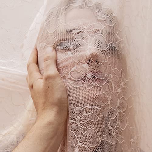 Woman’s face partially obscured by a delicate, floral lace fabric.