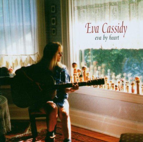 "Album cover: woman playing guitar by a window with 'Eva Cassidy' and 'eva by heart' text."