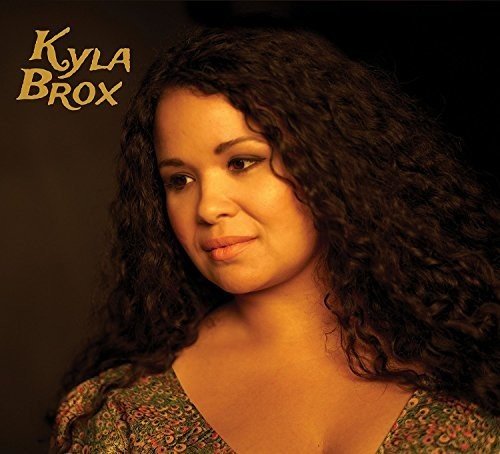 Close-up portrait of Kyla Brox with curly hair, album cover art.
