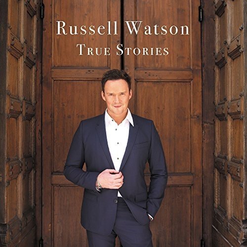 Man in dark suit stands before large wooden doors, album cover "Russell Watson True Stories".