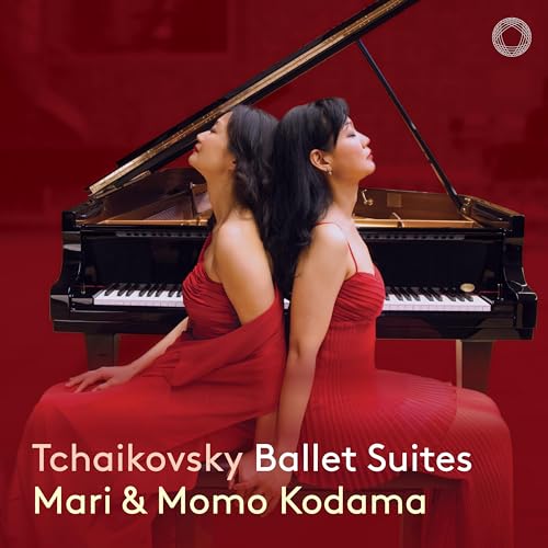 Two women in red dresses seated at a grand piano.