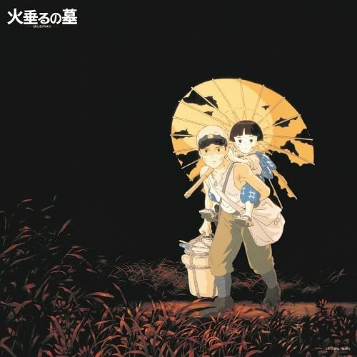 Two children with an umbrella stand in tall, reddish grass.