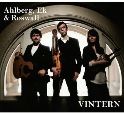 "Album cover with three musicians holding instruments, standing in an arched doorway."