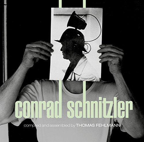 A man holds a black and white photo of a man's head with a lamp.