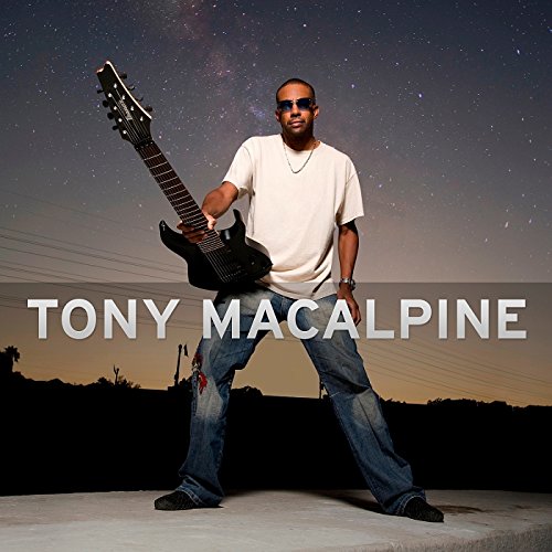 Man holding a black guitar, standing against a starry night sky.