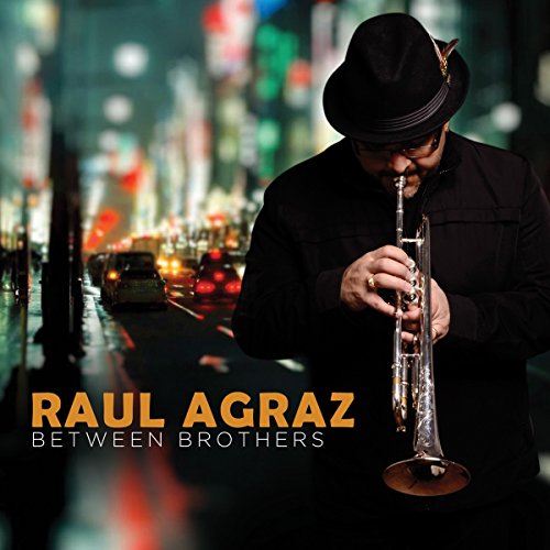 Man in black hat and shirt plays trumpet on a city street at night.