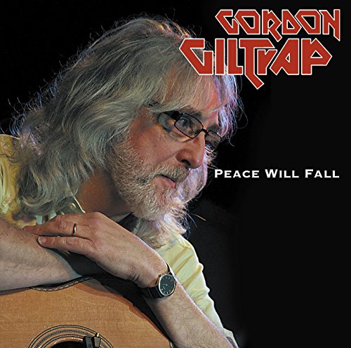Gordon Giltrap with long grey hair and glasses, holding an acoustic guitar.