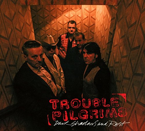 Band portrait of Trouble Pilgrims against a patterned, reddish-brown wall.