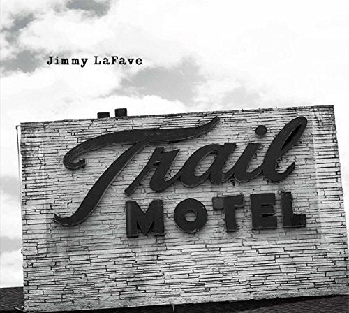 "Black and white image of a 'Trail Motel' sign on a brick building."