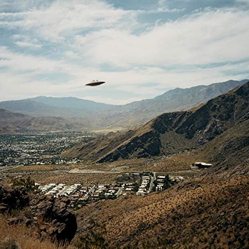 "Vinyl record cover featuring a UFO flying over a suburban town surrounded by mountains."