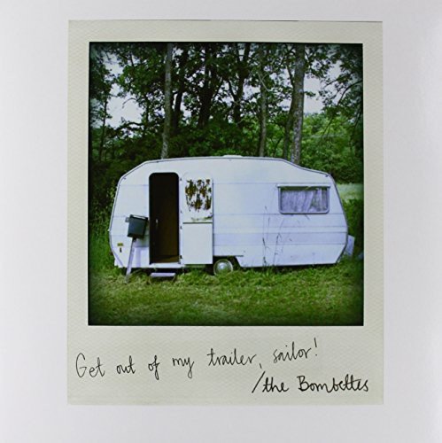 Polaroid-style image of a vintage white trailer in a wooded area.