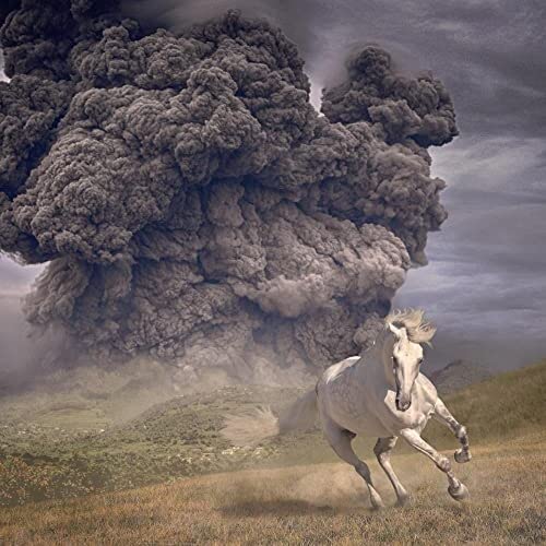 White horse running across a field with a volcanic eruption backdrop.