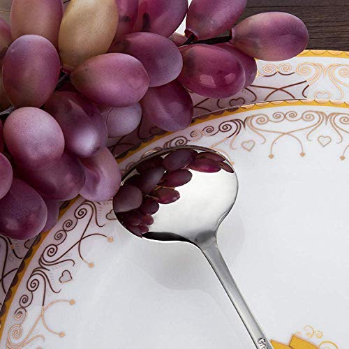 A bunch of purple grapes resting on a decorative plate with a silver spoon.