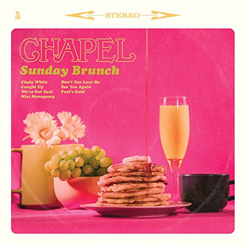 "Pink vinyl album cover with pancakes, flowers, and champagne on a table."