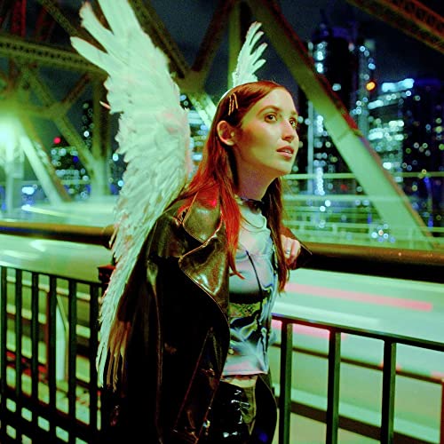 Woman with red hair and large white wings, city lights blurred.