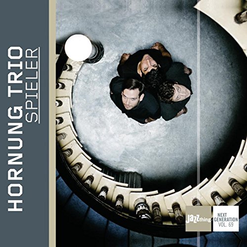 "Album cover with three men in black, viewed from above, in a circular staircase."