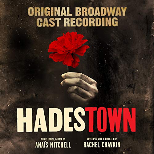 The alt text for the image is: "Album cover for 'Hadestown' featuring a hand holding a red flower."