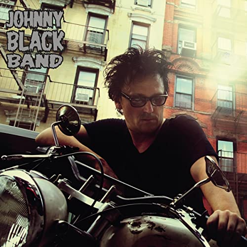 Album cover featuring a man on a motorcycle in front of buildings.