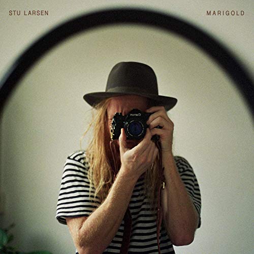 "Album cover featuring a man with a camera, wearing a hat and striped shirt."