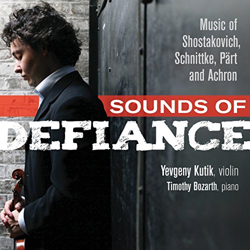 A man holding a violin stands beside a metal door, album cover in background.