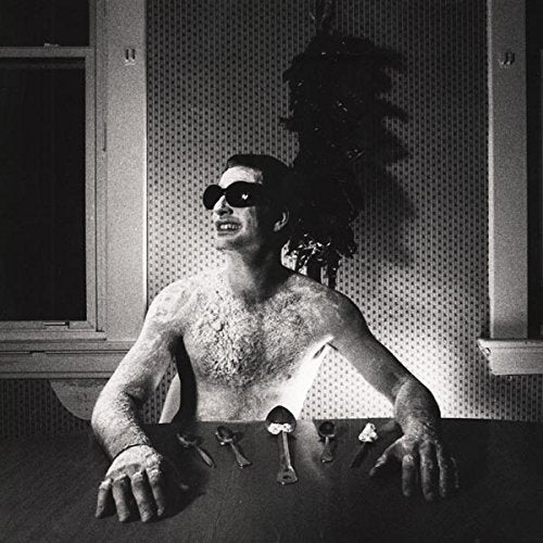 Black and white album cover featuring a shirtless man with sunglasses and silverware.