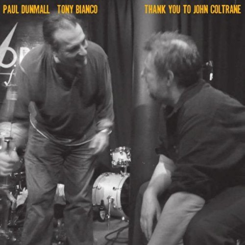 "Black and white image of two musicians on stage, album cover."