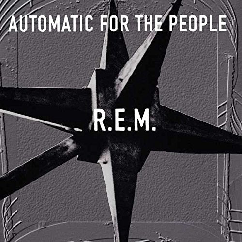 "Black and white R.E.M. album cover featuring a star-shaped object against a textured wall."