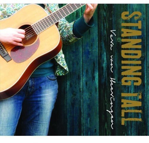 Album cover: person holding a guitar, against a green wooden fence background.