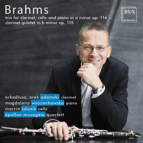Man in a black suit holding a clarinet, resting his chin on his hand.