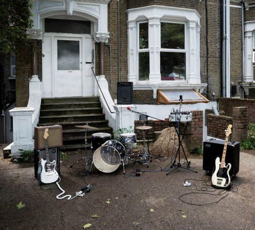 Drum kit and guitars set up on a residential front yard.