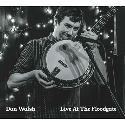Black and white photo of a man playing a banjo with a microphone.