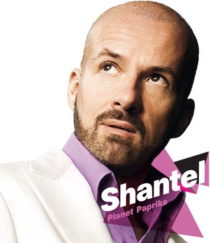 Bald man in white jacket with "Shantel Planet Paprika" text overlay on a white background.