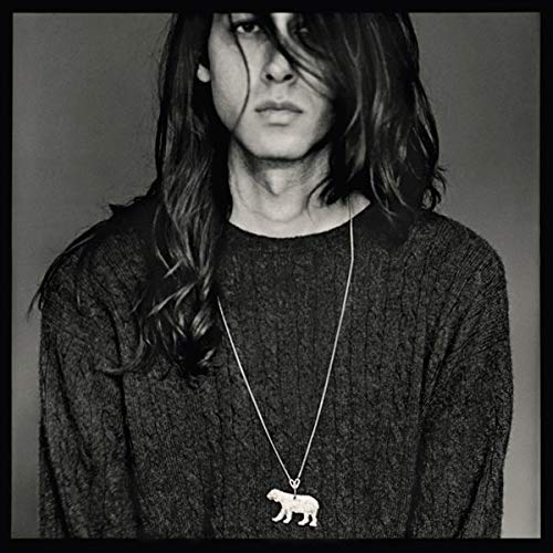 Black and white portrait of a person with long hair and a bear pendant.