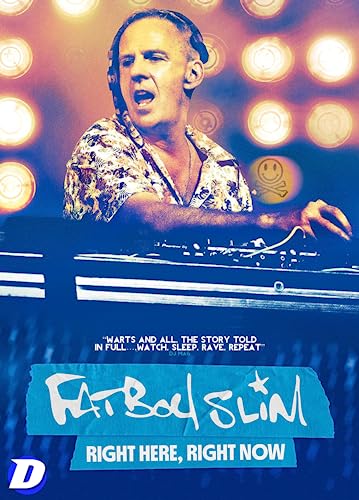 Fatboy Slim DJing in front of stage lights on a blue background.