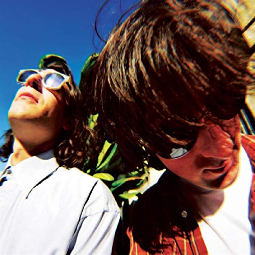 Two men wearing sunglasses look upwards against a blue sky.